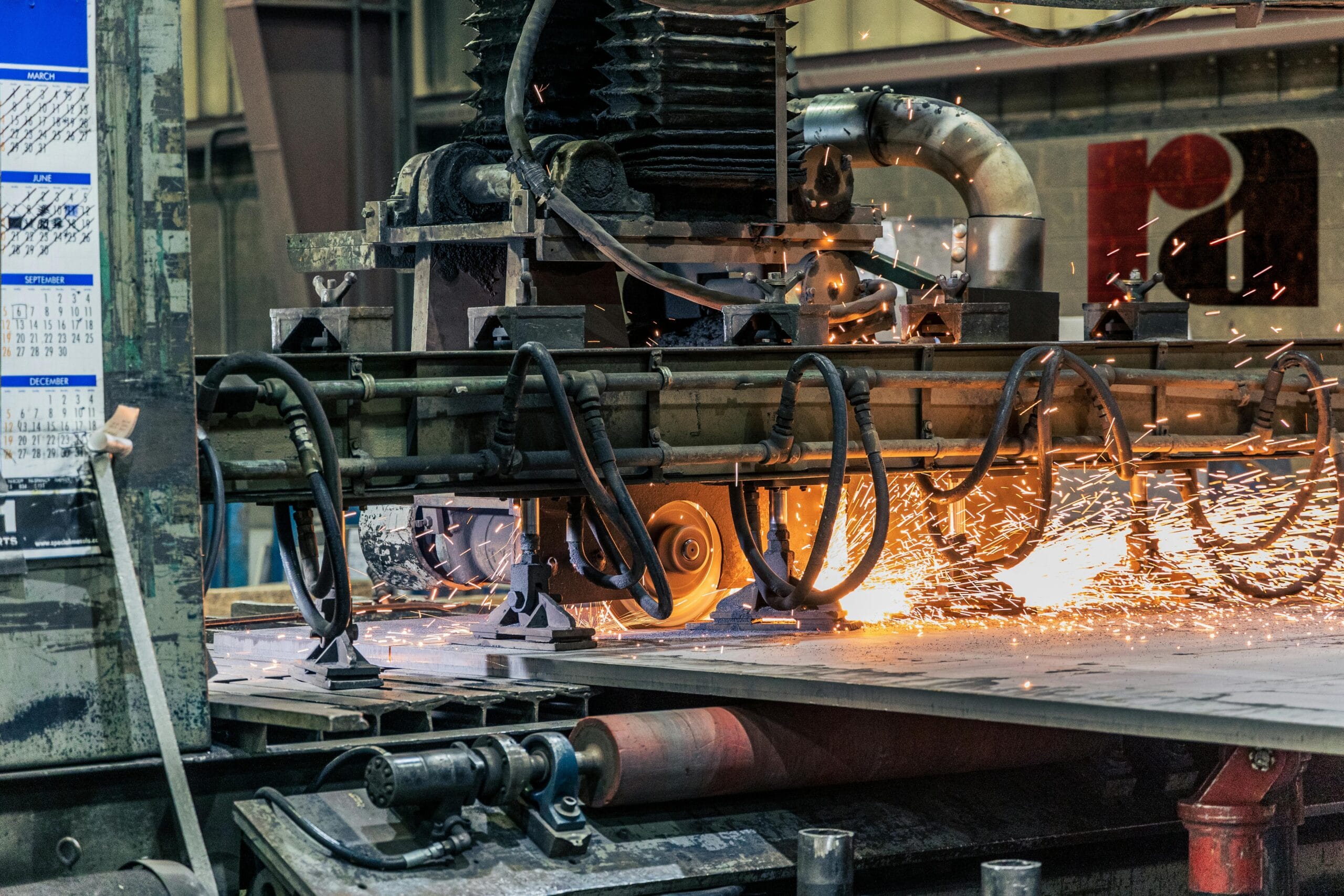 Detailed view of industrial machinery cutting metal, showcasing sparks and heat.